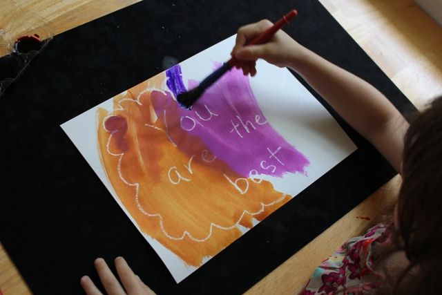 a child's hand holding a crayon marker over a piece of paper