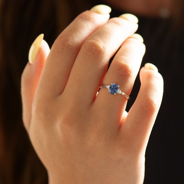 a woman's hand with a ring on it and a blue stone in the middle