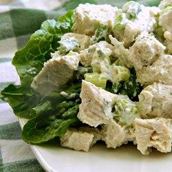 a salad with chicken and lettuce on a white plate sitting on a checkered table cloth