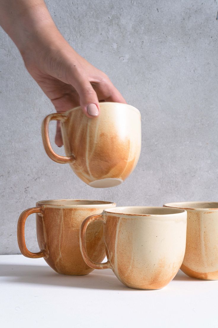 a person is pouring coffee into four mugs