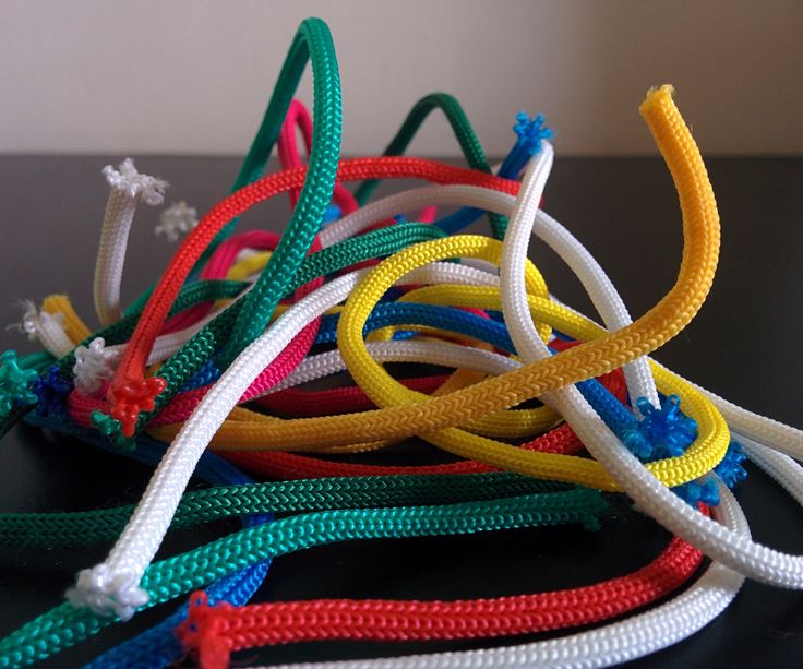 a bunch of colorful cords on a black table with white and red string attached to them