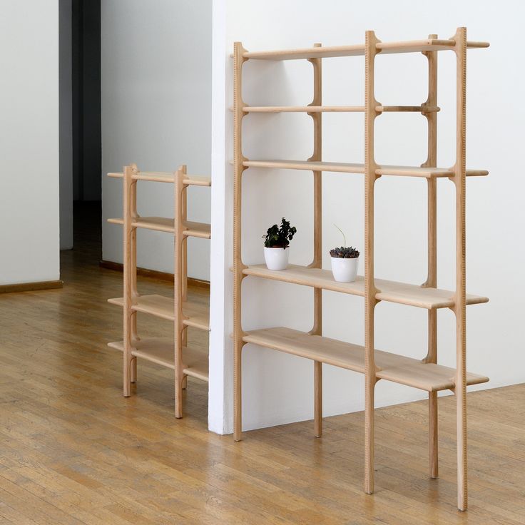 two wooden shelves with plants on them in front of a white wall and wood floor