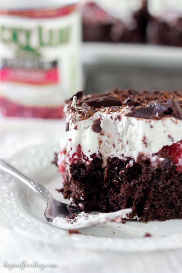 a piece of chocolate cake with whipped cream and cherries is on a white plate