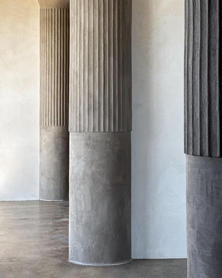 three large columns are lined up against the wall in an empty room with concrete flooring