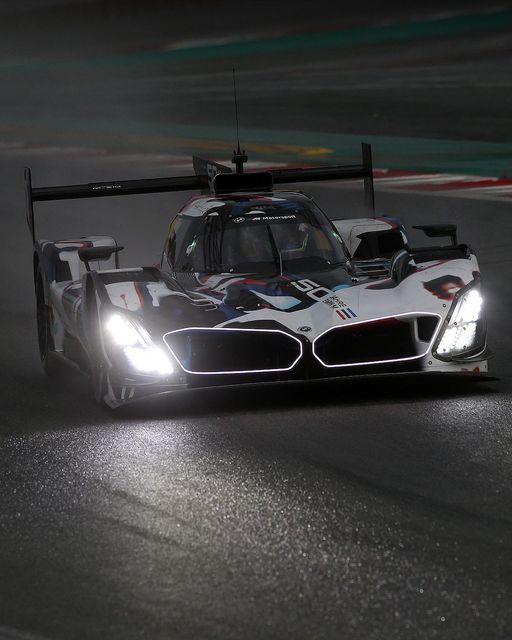 a racing car driving on a race track at night with lights on it's headlight