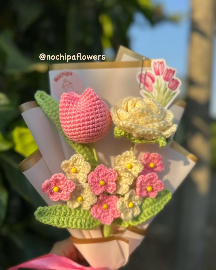 a crocheted bouquet of flowers is being held up by someone's hand