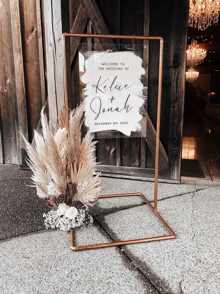 a sign that is sitting on the ground with some flowers in front of it and a bunch of feathers sticking out of it