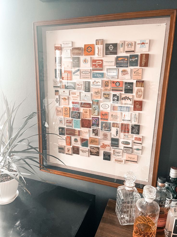 there is a framed photo on the wall with many different things in it and some bottles next to it