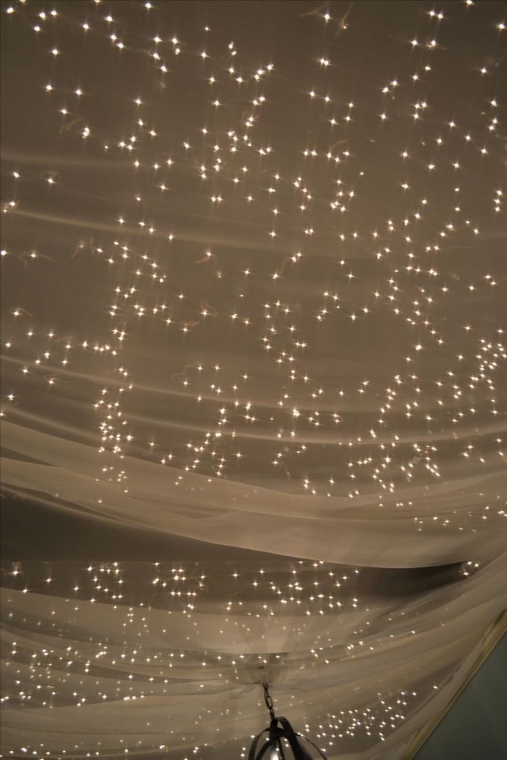 the ceiling is covered with white lights and draping in an area that looks like it has stars on it