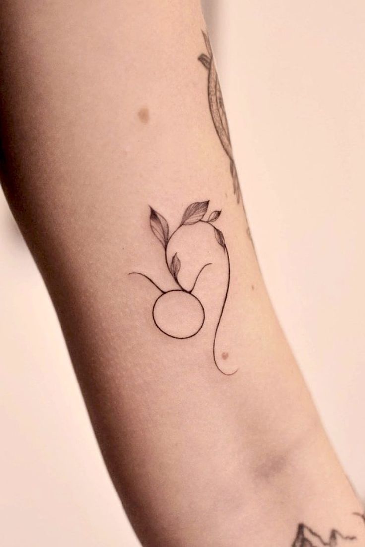 a woman's arm with a small apple tattoo on the left side of her arm