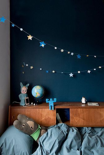 a child's bedroom with blue walls and stars on the wall above it,