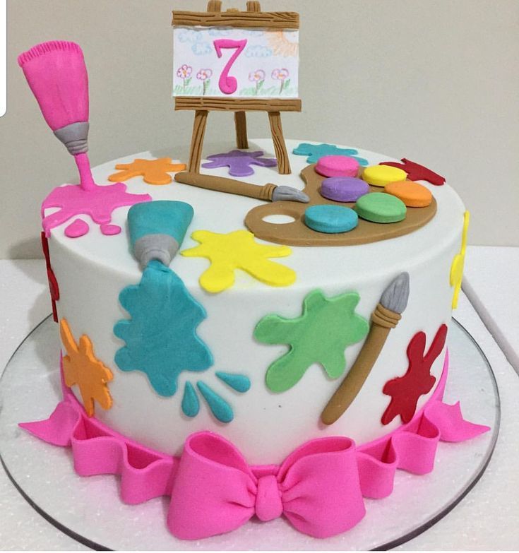 a birthday cake decorated with an artist's palette and pink bow