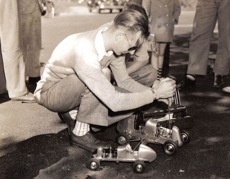 an old photo of a boy playing with his toy car