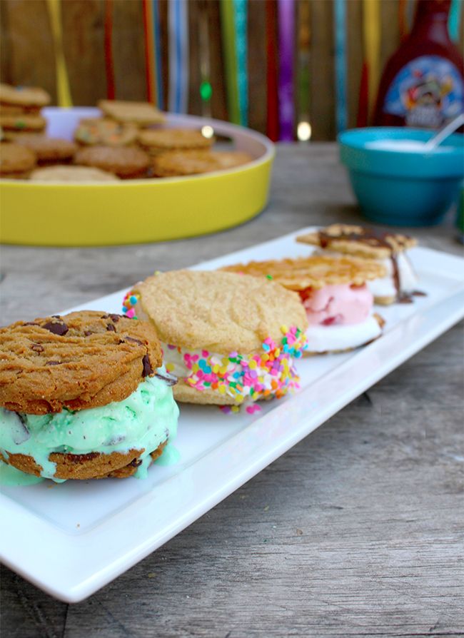 two ice cream sandwiches with sprinkles are on a white plate next to other desserts