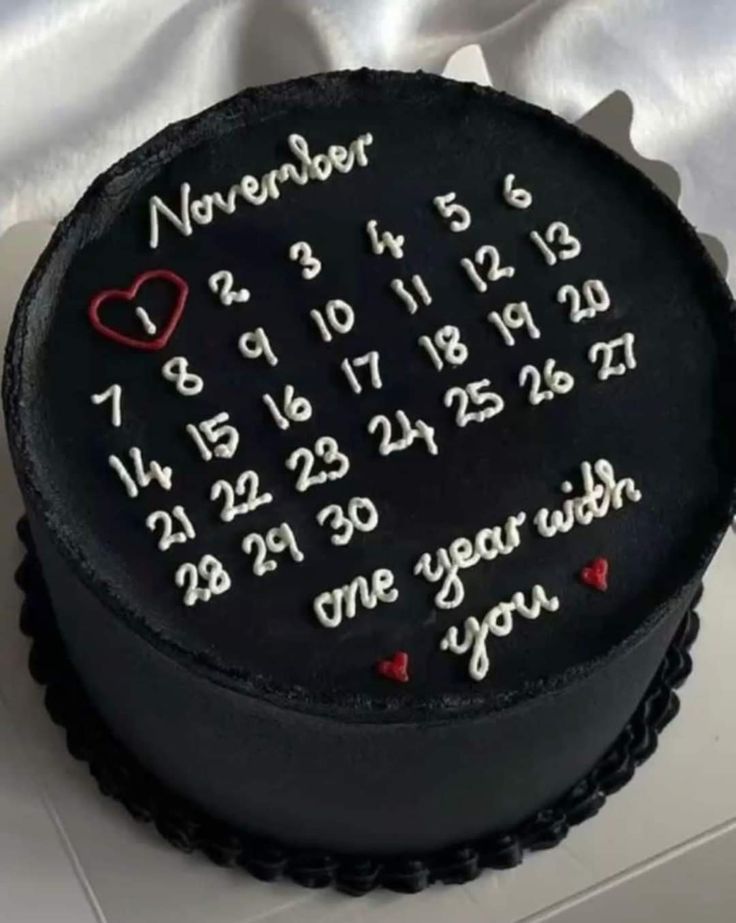 a black cake with white frosting and red hearts on the top that says november