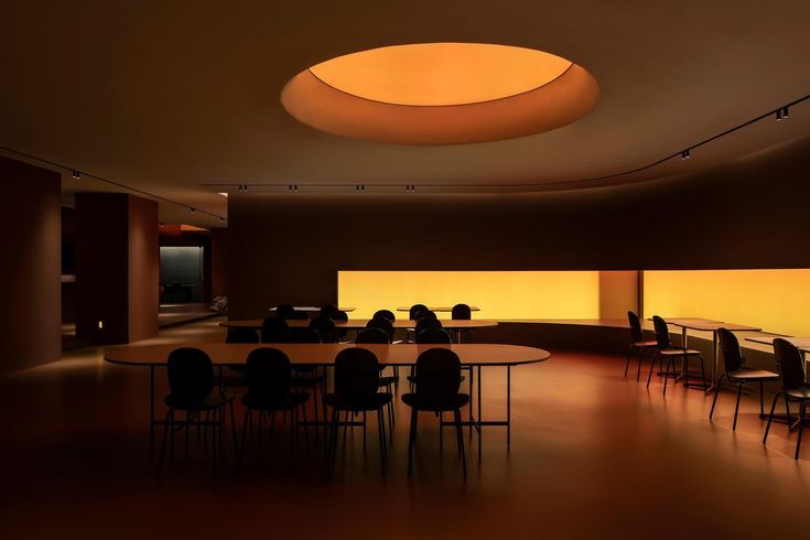 an empty conference room with round tables and chairs in the center, illuminated by yellow lights