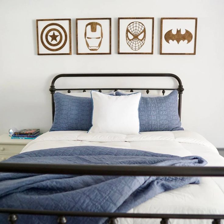 a bed with blue sheets and white pillows in a bedroom next to three framed pictures on the wall