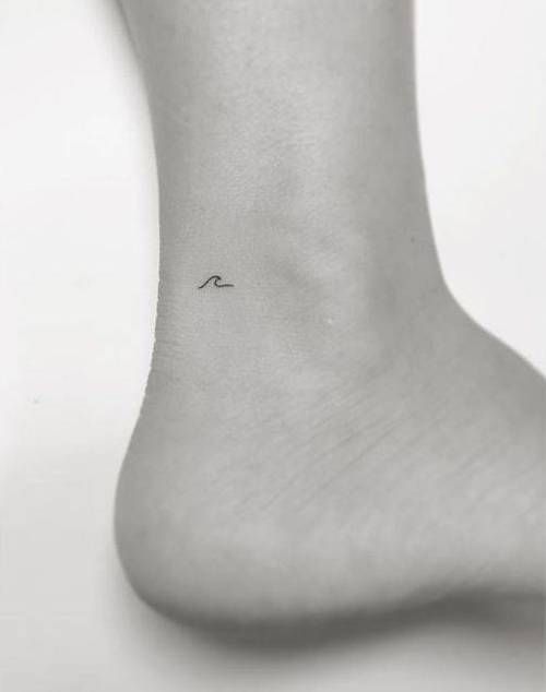 a small wave tattoo on the ankle is shown in black and white, as well as an