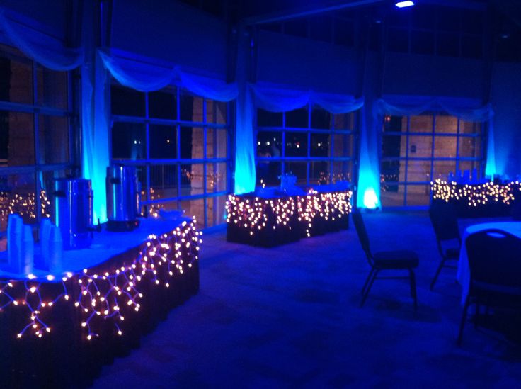 the room is lit up with blue lights and drapes on the windows, along with tables and chairs