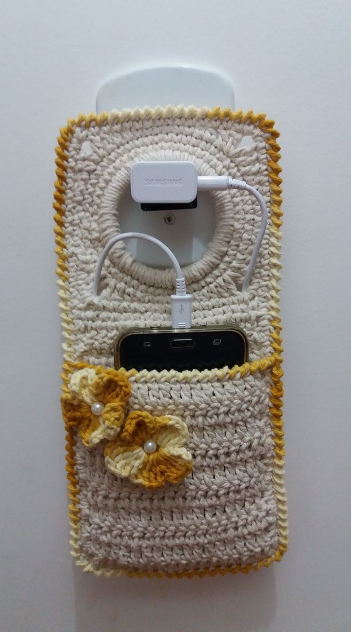 a cell phone with a crocheted case and charger attached to the back