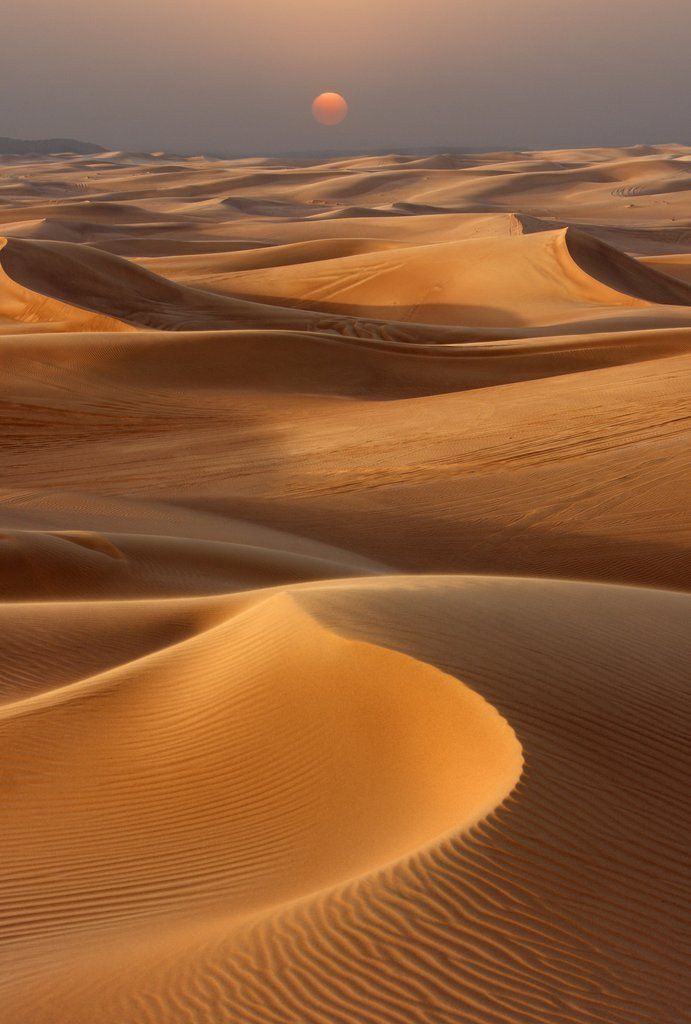 the sun is setting over some sand dunes