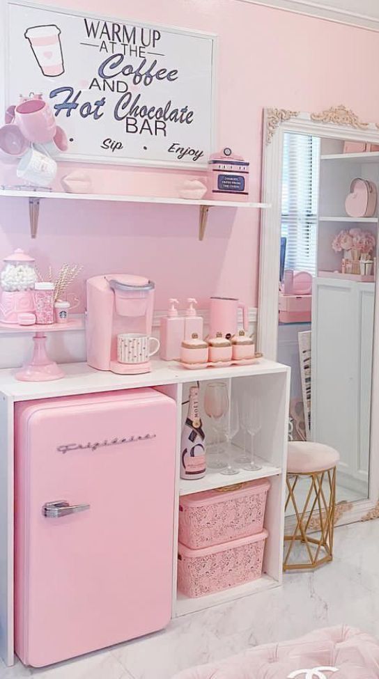 a pink kitchen with lots of items on the shelves