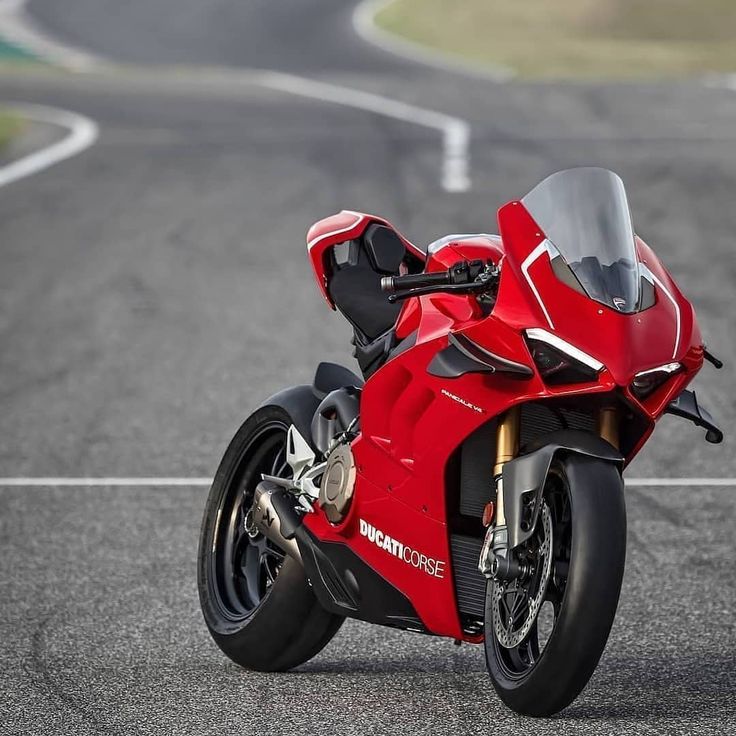 a red motorcycle parked on the side of a race track