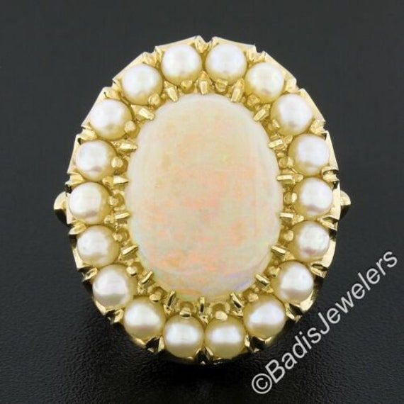 This gorgeous well made vintage ring is crafted in solid 14k yellow gold and features a stunning oval cabochon opal stone having a white base color and displays a light green and orange play throughout. The center stone is surrounded by a halo of 18 round ball shaped cultured pearls. This vintage ring is in excellent condition, and ready to make a statement! Enjoy :) --Stone(s):-- (1) Natural Genuine Opal - Oval Cabochon Cut - Multi Prong Set - White Base w/ Light Green and Orange Play - 16.3x12 Luxury Oval Cabochon Pearl Ring, Luxury Hallmarked Oval Cabochon Opal Ring, Classic Oval Opal Ring Collectible, Oval Cabochon Opal Ring Fine Jewelry, Oval Cabochon Opal Ring In Fine Jewelry, Fine Jewelry Oval Cabochon Opal Ring, Gold Multi-stone Opal Ring With Oval Cabochon, Antique Oval Pearl Ring Stamped 14k, Heirloom Oval Opal Ring With Multi-stone