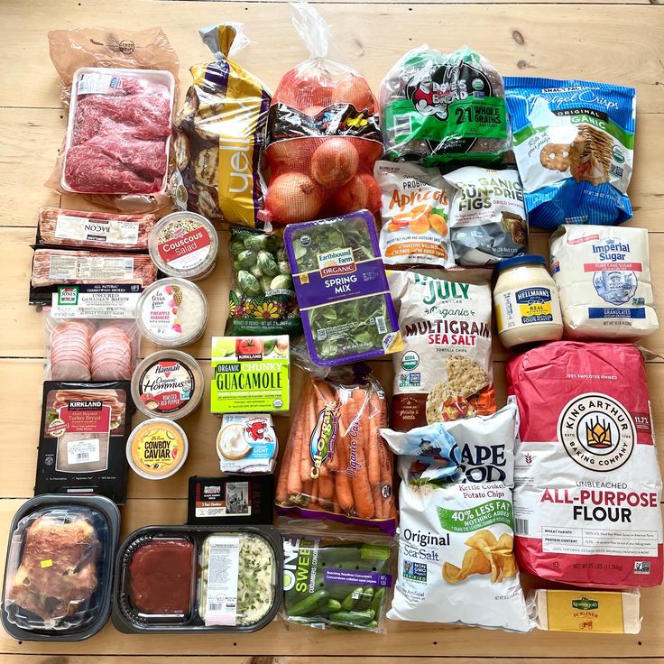 an assortment of food is laid out on a table with plastic bags and other items