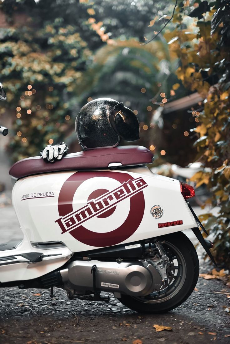 a motor scooter with a helmet on the back is parked in front of some trees