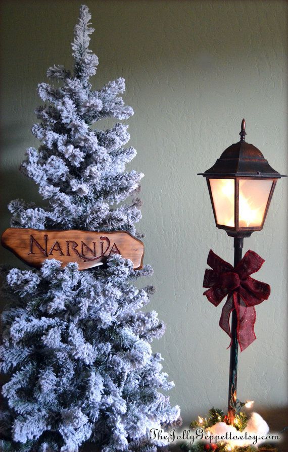 a small christmas tree next to a lamppost with a name on it and a wooden sign