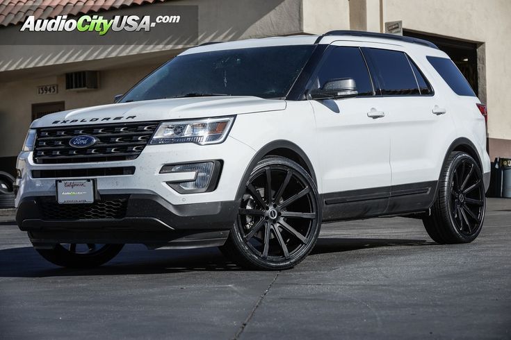 the white ford explorer is parked in front of a building with an american flag on it