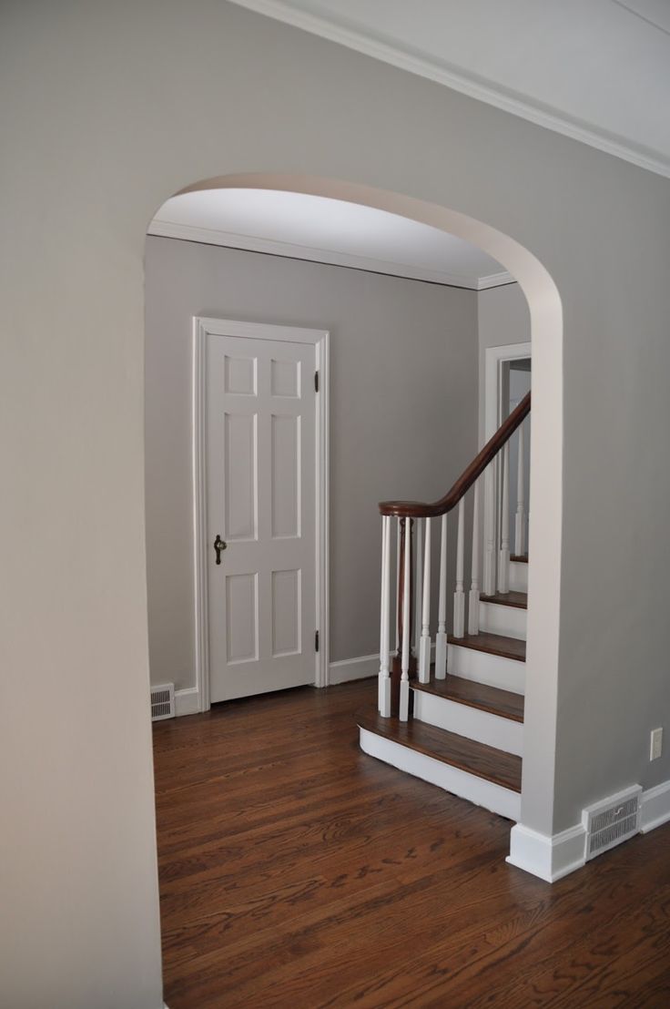 an empty entryway with wooden floors and white doors