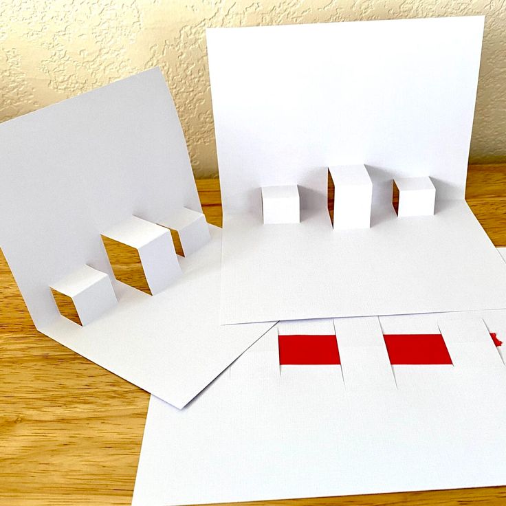 three pieces of white paper with red squares on them