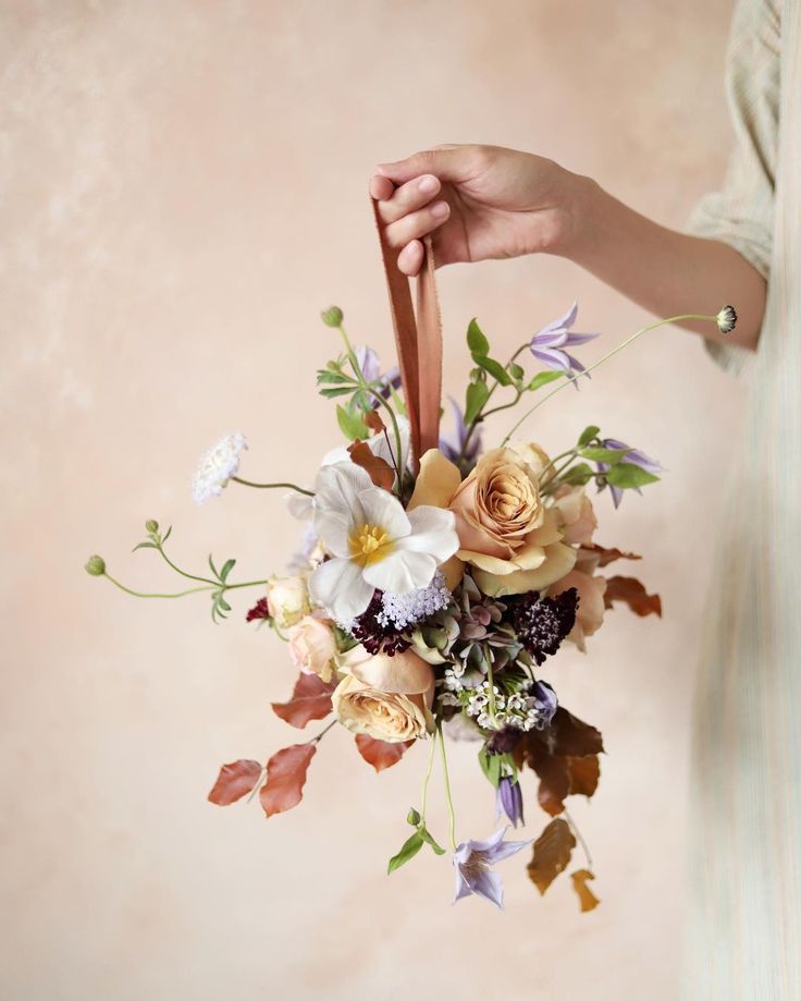 a woman is holding a bouquet of flowers in her left hand and the other hand