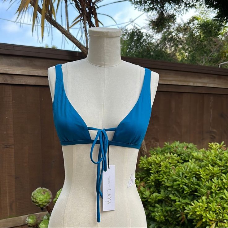 The Dreamer Top By Laya Swim Is A Deep Plunge Triangle Top With Wide Adjustable Straps And A Front Tie. The Flattering Silhouette Offers A Supportive Under-Bust Band, An Accentuating V Neckline, Wide Straps And An Adjustable Front Tie To Wear The Top Three Ways! This Bikini Top Has Luxurious Features Which Include A Matte Finish, Double Lining For Comfort And Support And A Seamless Finish. Features Deep Plunge Triangle Top Adjustable Straps Front Tie To Style Multiple Ways Matte Finish Fully Lin Chic Blue Swimwear With Tie Back, Low-cut Blue Summer Tops, Adjustable Straps V-neck Swimwear For Pool, Maternity Tankini, Multicolor V-neck Stretch Swimwear, Blue Stretch V-neck Swimwear, Bandeau Tankini Top, Nylon Swimwear With Built-in Bra Triangle Top, Multicolor Stretch V-neck Swimwear