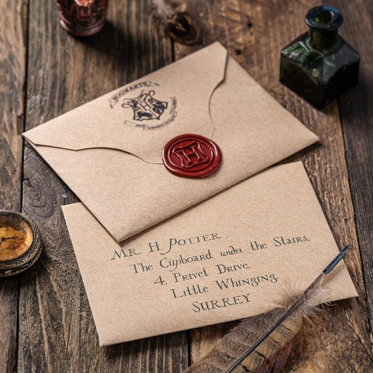 an envelope with a wax stamp on it and some writing paper next to ink pens