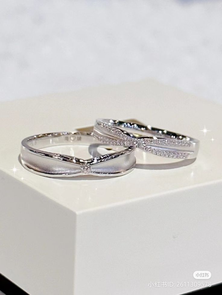 two wedding rings sitting on top of a white box