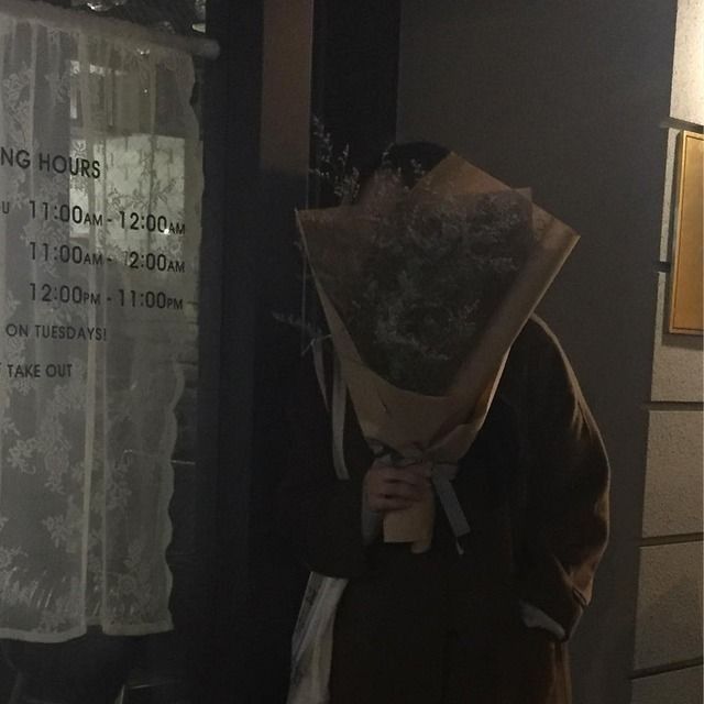 a person standing in front of a window with a bouquet on their head and a sign that says no hours