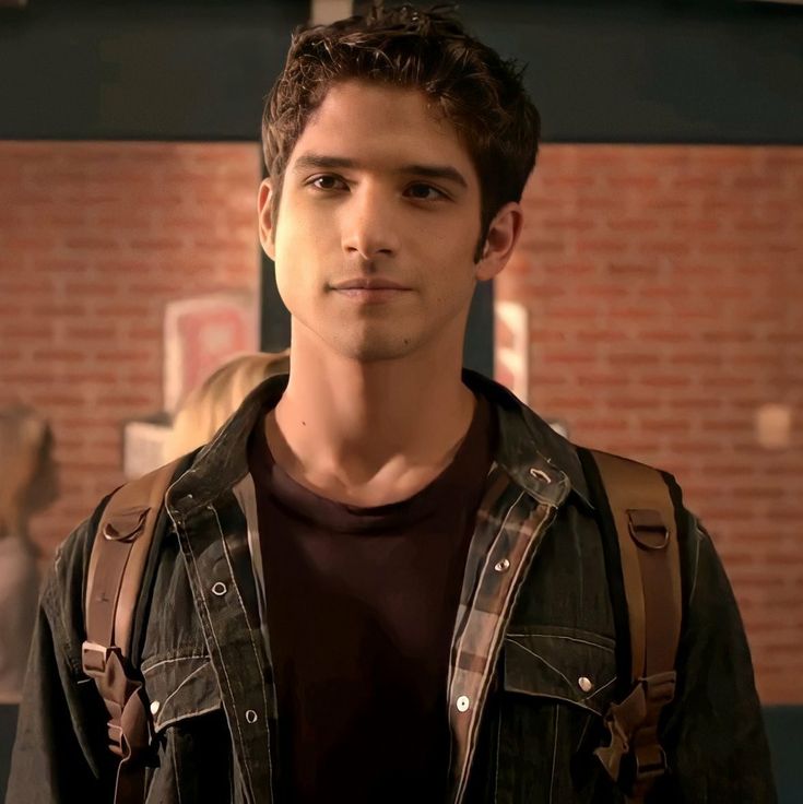 a young man standing in front of a brick wall