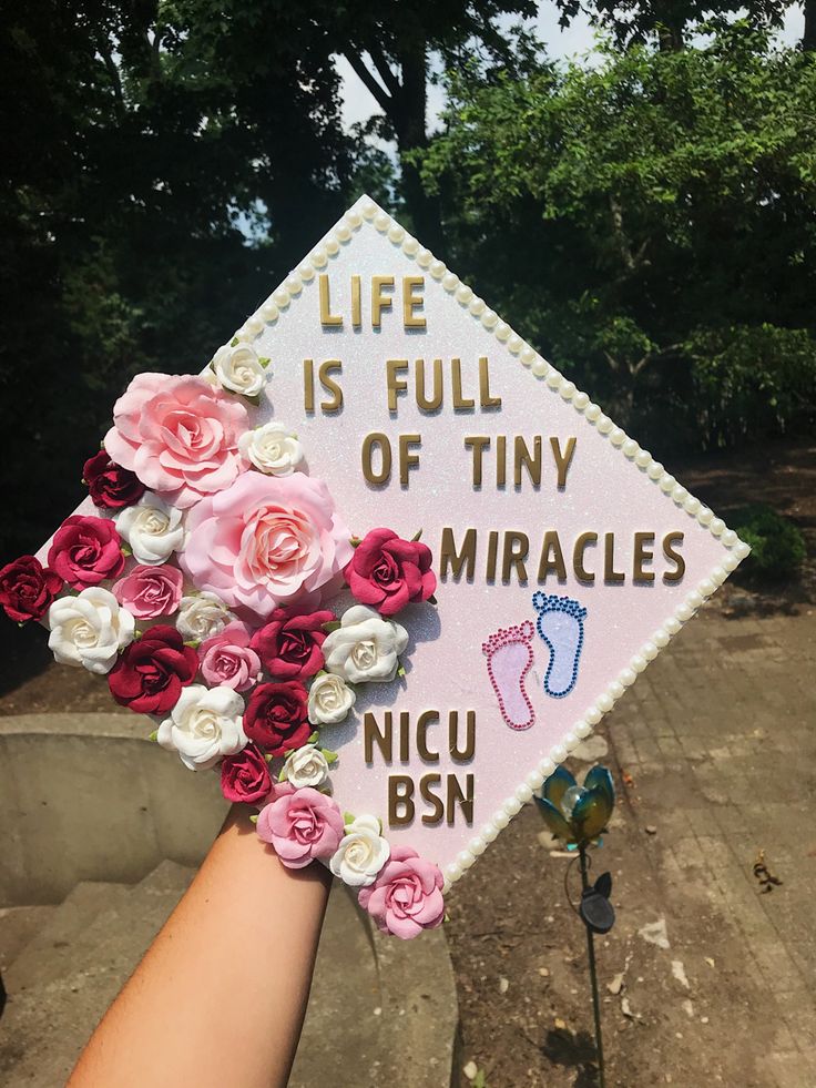 someone is holding up a graduation cap with flowers on it that says life is full of tiny miracless nicu bsn