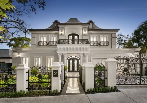 a large white house with lots of windows and wrought iron gates on the front entrance