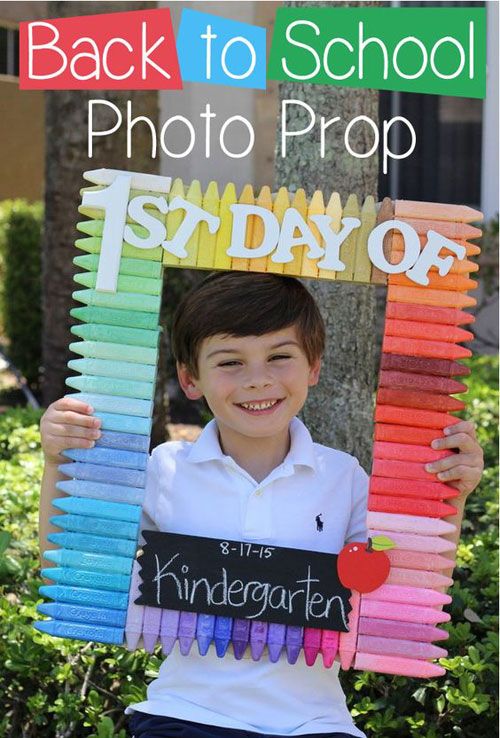 a young boy holding up a sign made out of colored crayons and the words 1st day of school written on it