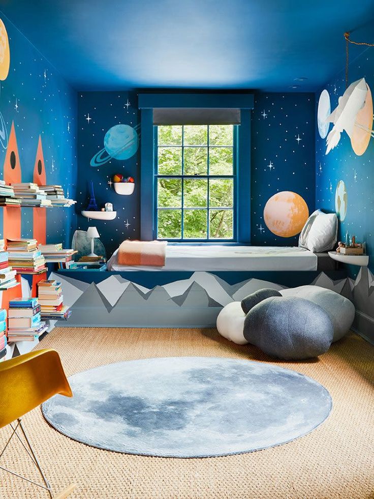 a bedroom with blue walls and space themed decor on the wall, along with bookshelves