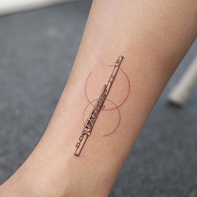 a tattoo on the leg of a woman with a musical instrument in her left foot