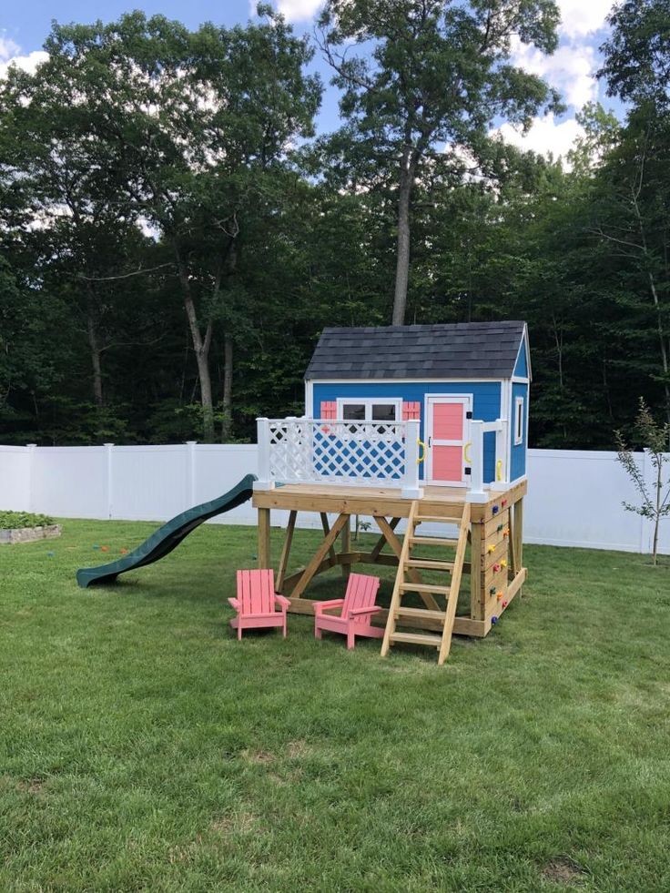 a play house with a slide and chairs in the yard