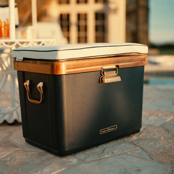 a black and gold cooler sitting on top of a stone floor