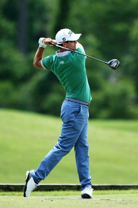 a man swinging a golf club at a green course