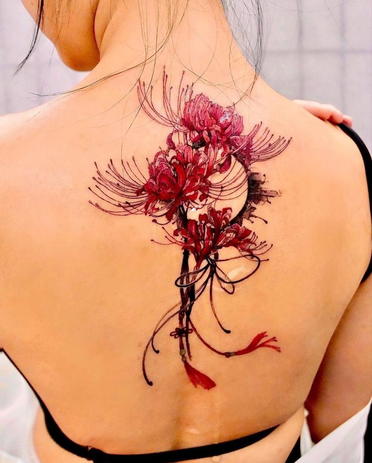 the back of a woman's shoulder with flowers painted on it and red ink