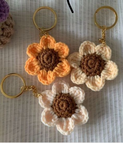 three crocheted flower keychains sitting on top of a white tablecloth